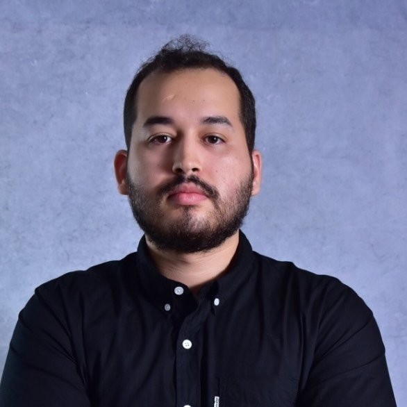 dinario olhando para frente com fundo cinza atrás.